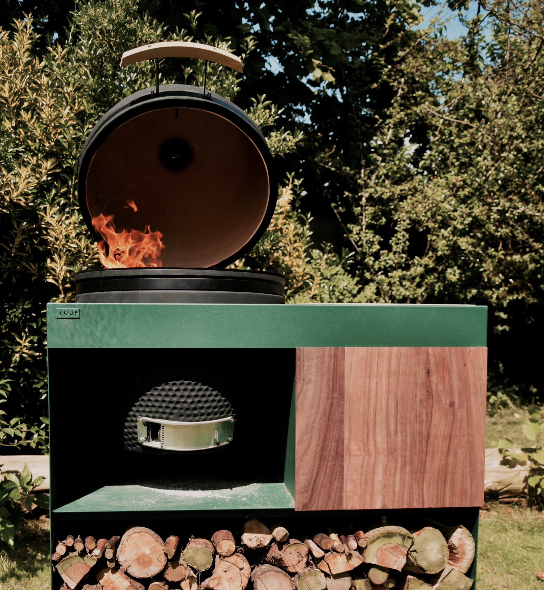 KUJP BBQ onderstel in groen gepoederlakt staal met brandende barbecue en houtopslag